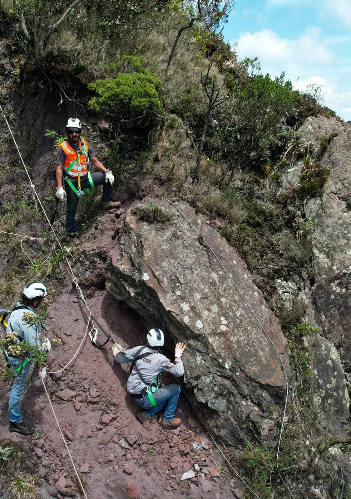 Equipe de alpinismo industrial com EPI avaliando rocha em encosta