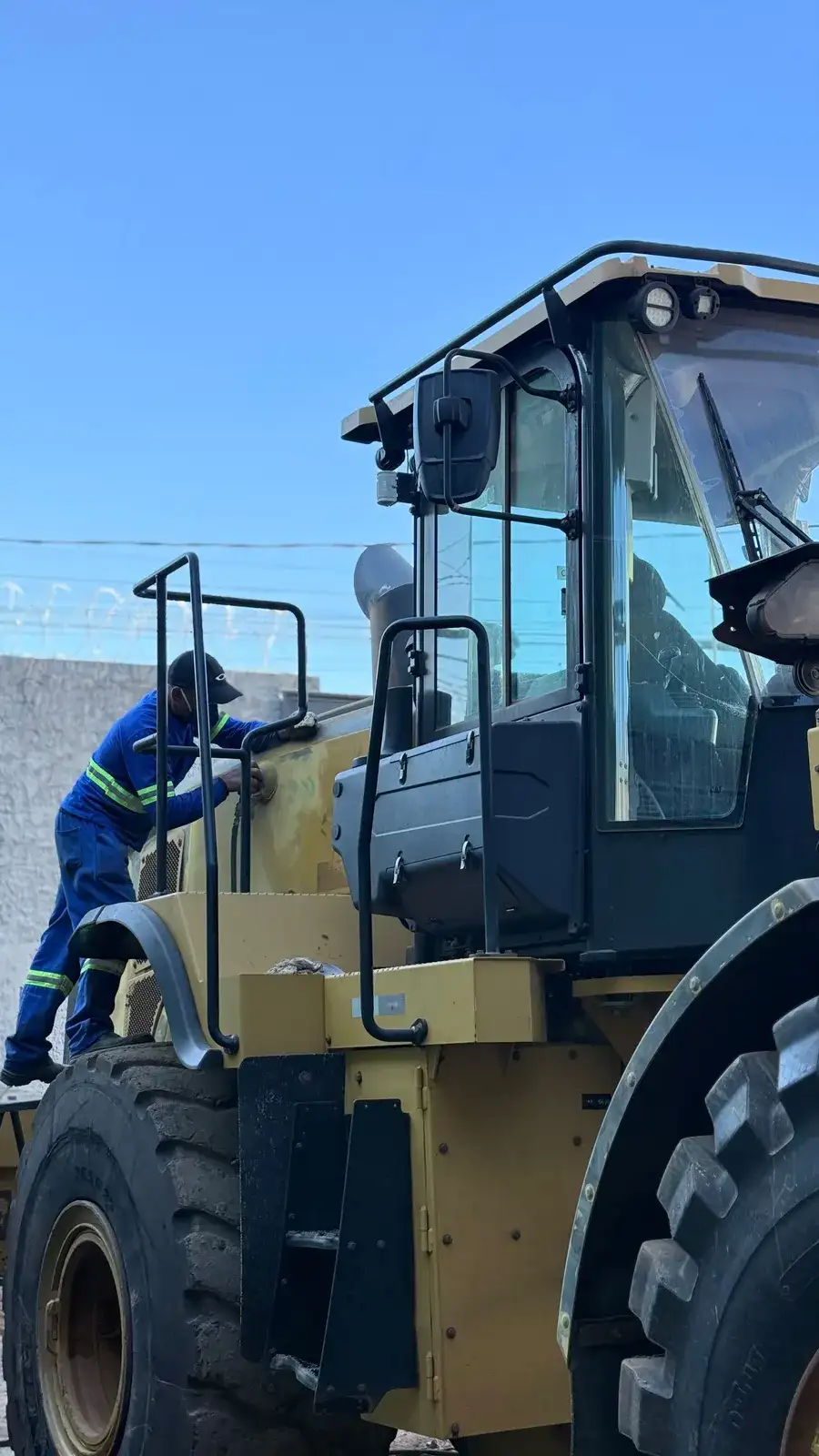 Mecânico subindo na cabine de uma pá carregadeira para inspeção
