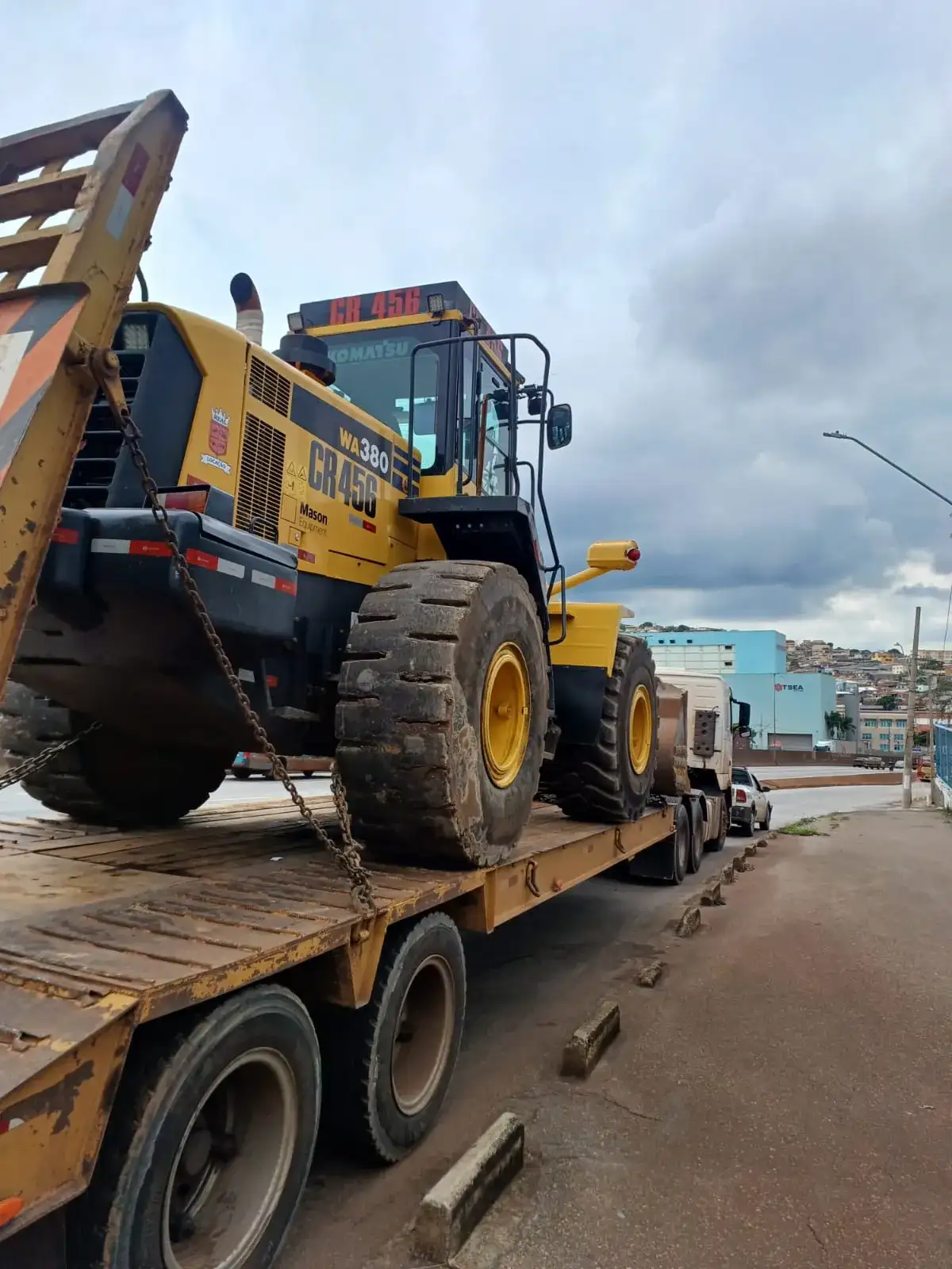 Pá carregadeira embarcada em caminhão prancha para transporte